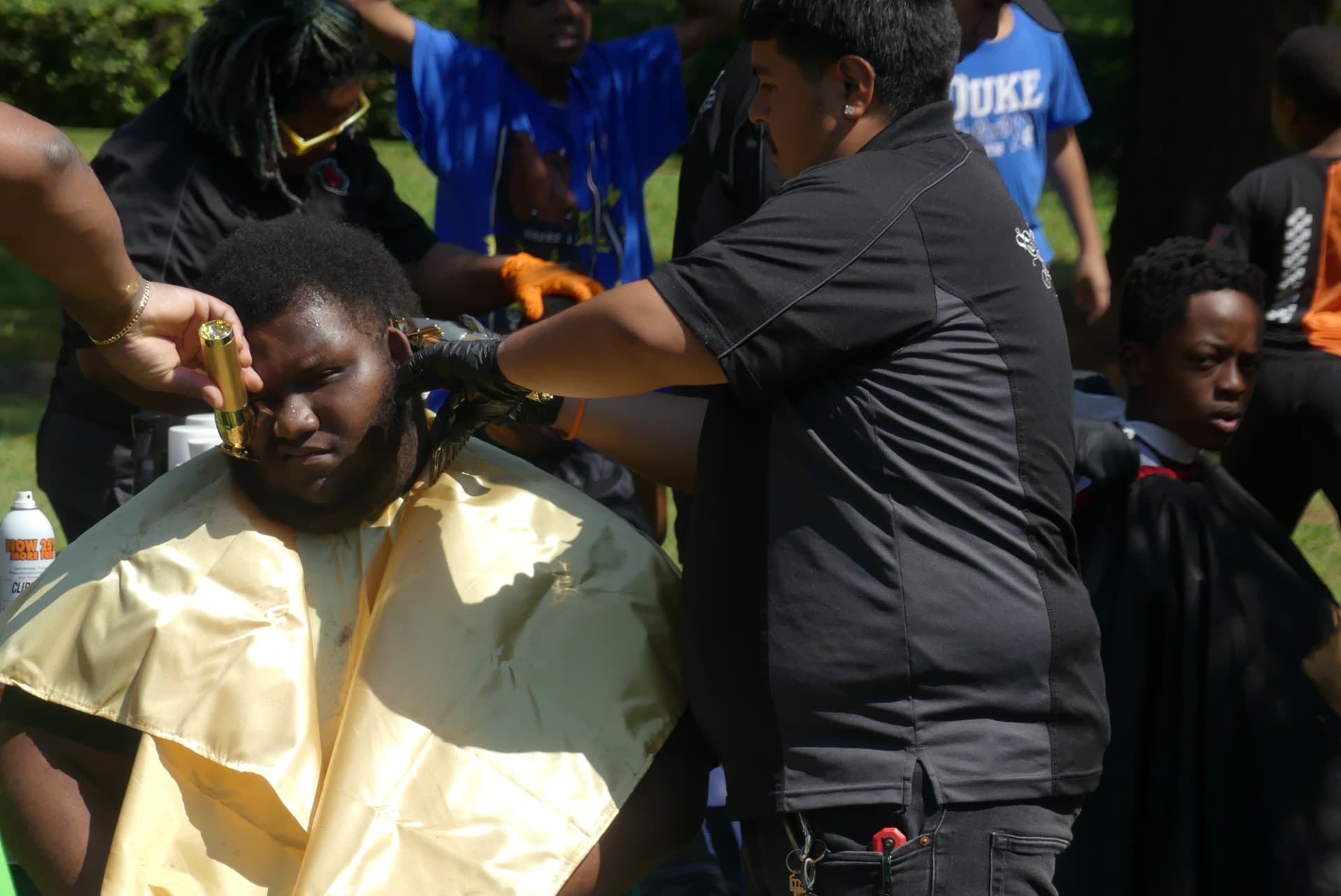 A student getting a free haircut at the outdoor barbershop